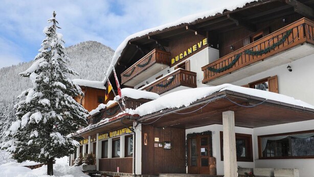 A snow-covered building with a wooden facade, balconies, and a sign that reads "Hotel Rainer." - Hotel Bucaneve (Moena)