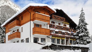 A multi-story wooden building with balconies, a restaurant bar, and a hotel sign. - Hotel Bucaneve (Moena)
