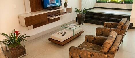Una sala de estar moderna con un conjunto de sofá, una mesa de centro, un televisor en un estante de madera y una planta en maceta.
