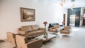 Een moderne woonkamer met een beige bank, een glazen salontafel en een zwarte leren bank.