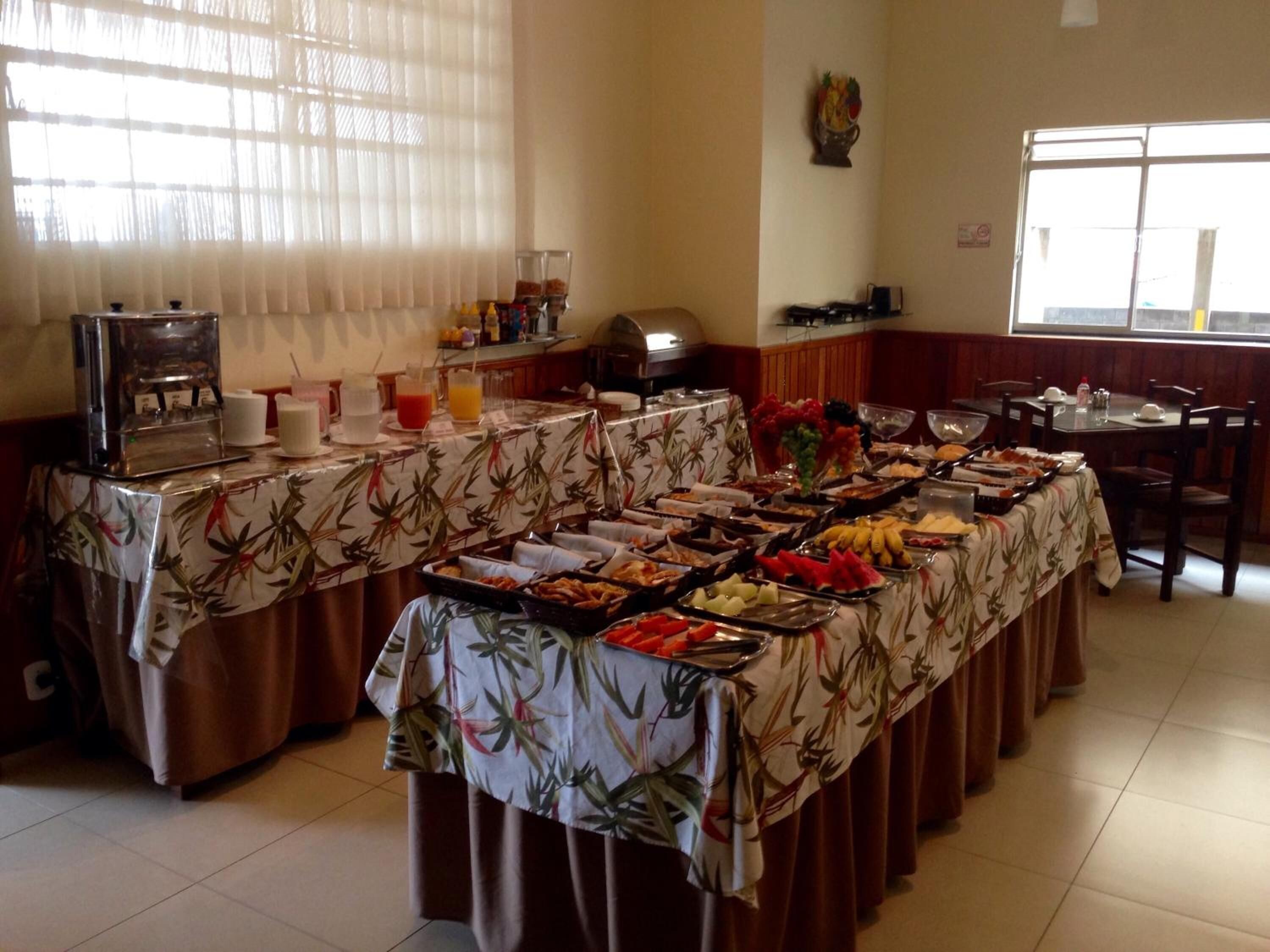 Ein reichhaltiges Buffet mit verschiedenen Speisen und Getränken, eine Kaffeemaschine sowie ein Essbereich mit Stühlen und Tischen.