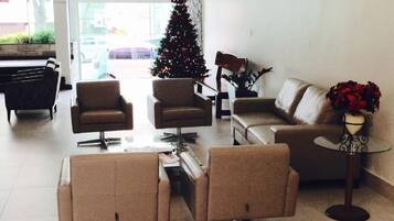 Una sala moderna con un árbol de Navidad, sofás de cuero y una mesa de centro de vidrio.