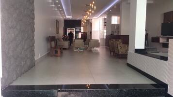 A spacious lobby with a marble staircase, seating area, and a reception desk.