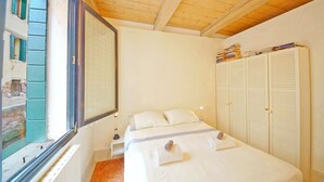 A bedroom with a bed, a window, a wardrobe, and a radiator.