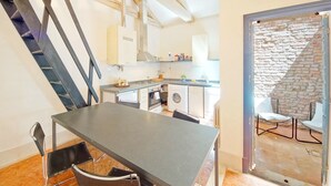 A modern kitchen with a dining area, a staircase, and a view of the outside.
