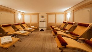 A room with multiple sun loungers arranged in a semi-circle, wooden floors, and a central white cabinet. - Hotel Jagdhof (Selva di Val Gardena)