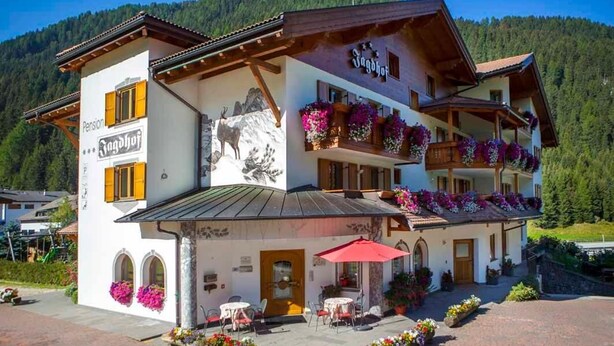 A two-story building with a mountain backdrop, featuring a sign that reads "Jagdhof." - Hotel Jagdhof (Selva di Val Gardena)