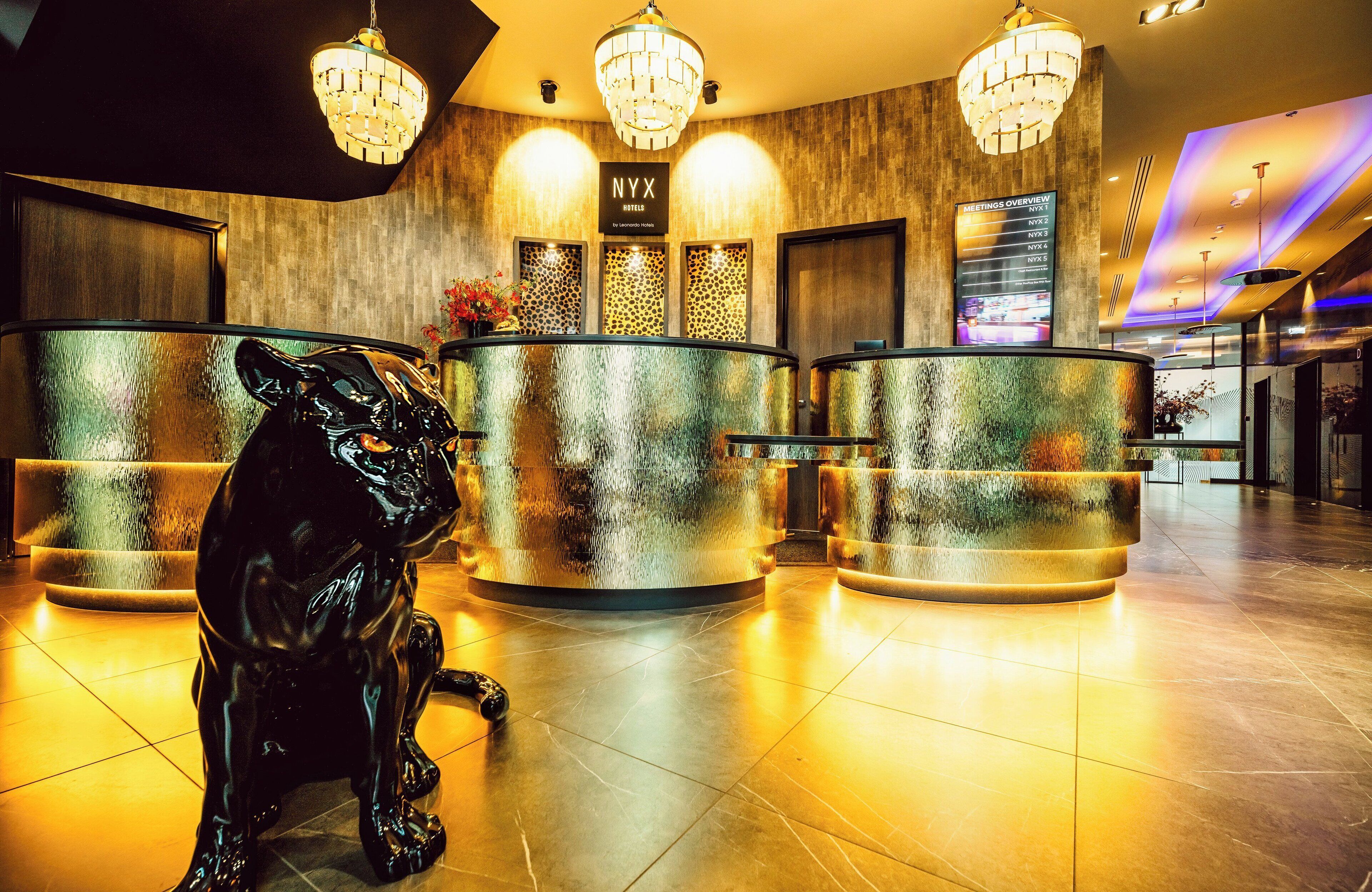 A reception area with a black panther statue, a reception desk, and a 'Meetings Overview' sign.