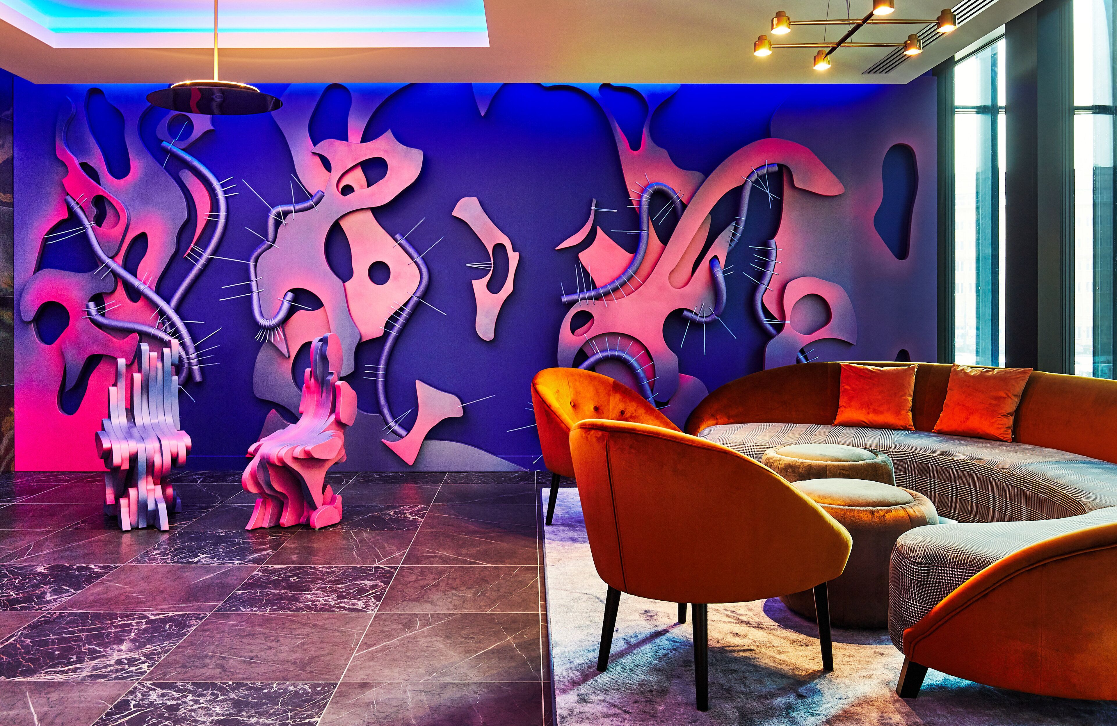 A modern interior with abstract wall art, a sofa, and chairs.