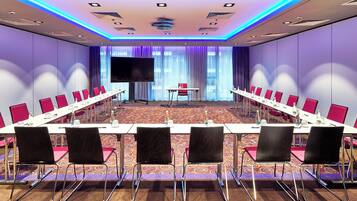 A conference room with a long table, chairs, a TV, and a small table with a red chair.