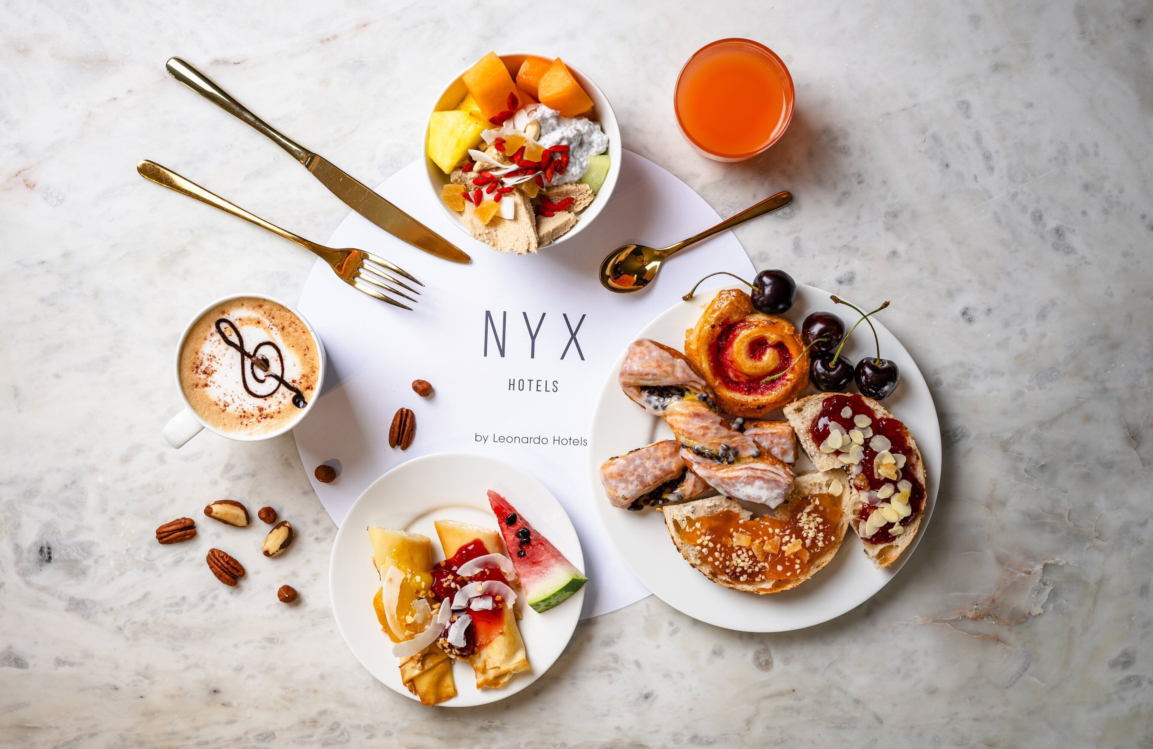 A breakfast setting with a variety of foods, including pancakes, fruit, and a cup of coffee, arranged on a marble table.