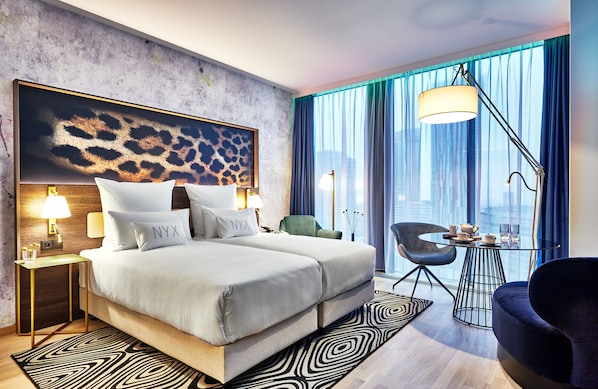 Una habitación de hotel moderna con una cama grande, un escritorio y vistas a la ciudad.