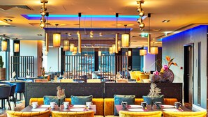 A restaurant with yellow chairs, tables, and hanging lights. - NYX Hotel Warsaw by Leonardo Hotels (Warsaw)
