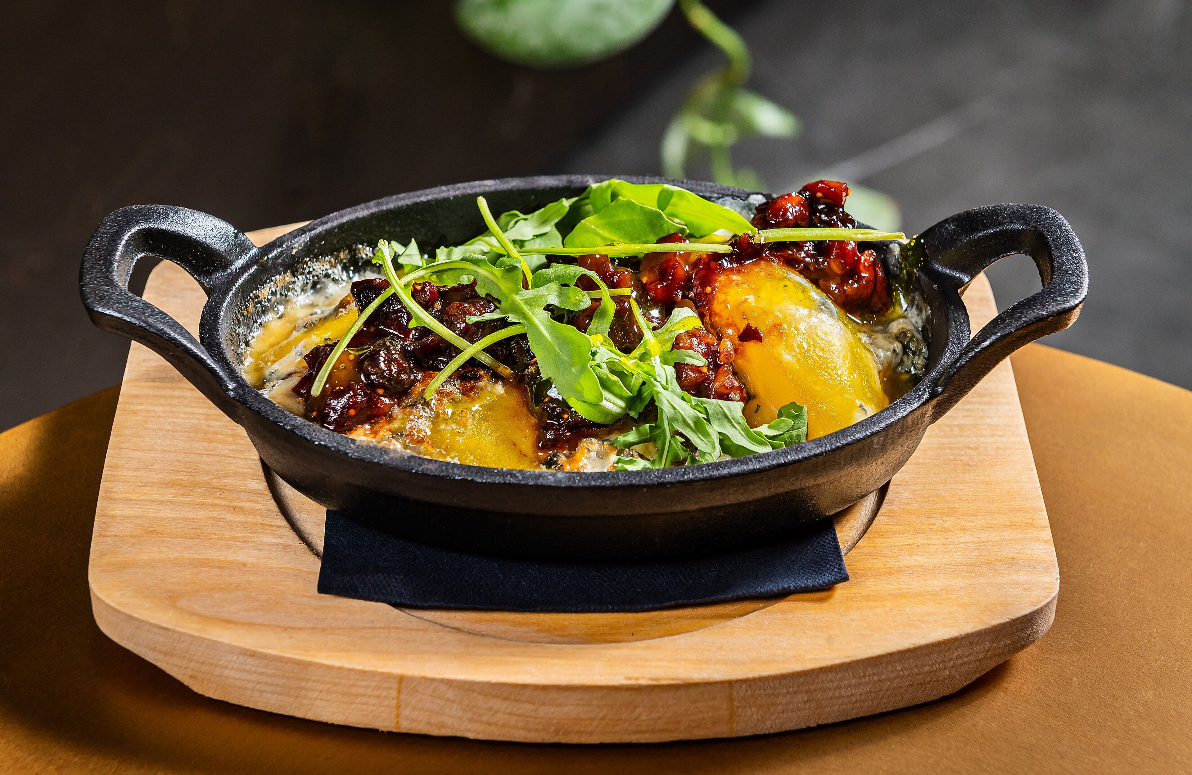 A cast iron skillet with food on a wooden board.