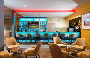 A bar area with multiple seating options and a television screen displaying a sports event. - Leonardo Hotel Offenbach Frankfurt (Offenbach am Main)
