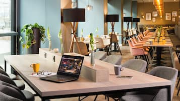 Una sala de conferencias moderna con una larga mesa, sillas y una computadora portátil sobre la mesa.