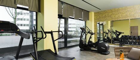 Un gimnasio con cintas de correr, elípticas y una zona de pesas.