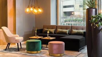 Un espace de détente moderne comprenant un canapé, des fauteuils, des poufs et un luminaire suspendu.