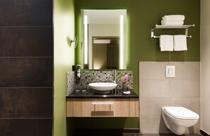 Un baño moderno con un espejo grande, un lavabo y un inodoro.