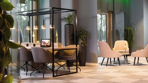 A modern hotel lobby with a seating area, a reception desk, and large windows with green lighting. - Leonardo Hotel Offenbach Frankfurt (Offenbach am Main)