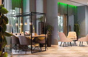 A modern hotel lobby with a seating area, a reception desk, and large windows with green lighting. - Leonardo Hotel Offenbach Frankfurt (Offenbach am Main)