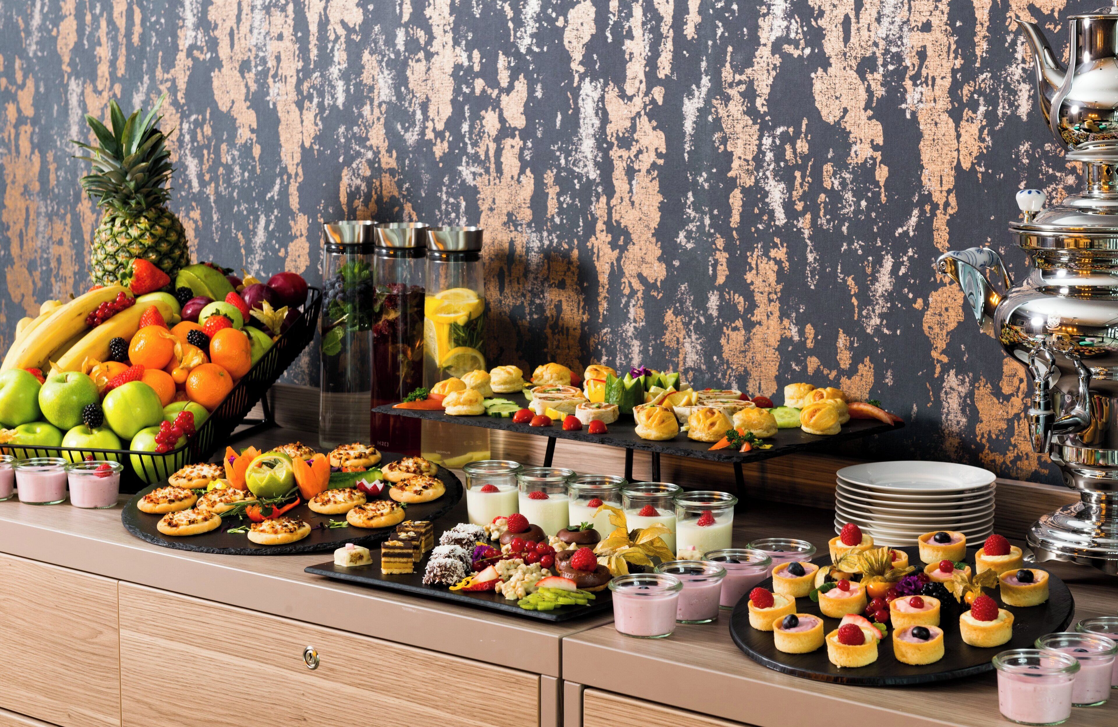 Un tavolo da buffet con diversi cibi e un elegante teiera d'argento.