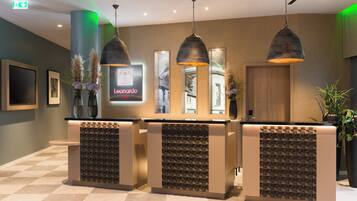 A reception area with a modern design, featuring a reception desk, pendant lighting, and a wall-mounted sign.