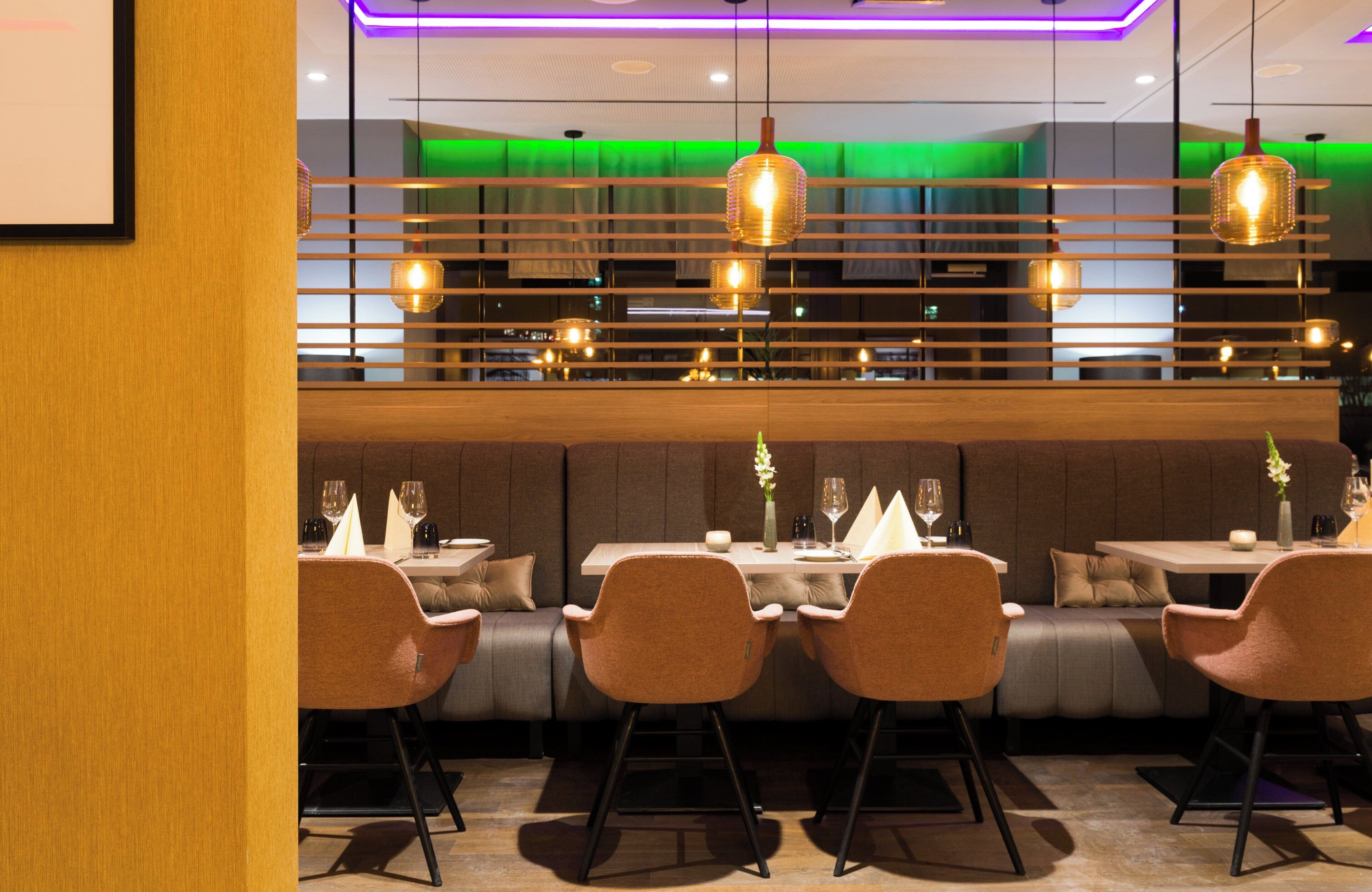 L’intérieur d’un restaurant au design moderne, avec une longue table à manger entourée de chaises, un bar et des luminaires suspendus.