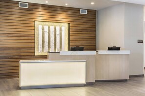 A reception desk with a modern design, a wooden wall paneling, and a framed artwork above it. - Fairfield Inn & Suites by Marriott Minneapolis North/Blaine (Blaine)
