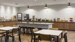 Un espace cuisine moderne doté d’un îlot central, de tabourets de bar et d’un coin repas avec des tables et des chaises.