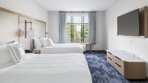 Une chambre d’hôtel avec deux lits, une télévision, un bureau et une fenêtre avec des rideaux.
