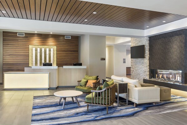 A modern lobby with a reception desk, seating area, and a fireplace. - Fairfield Inn & Suites by Marriott Minneapolis North/Blaine (Blaine)