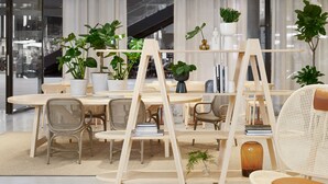 A modern, well-lit room with a round table, several chairs, and a wooden easel. There are multiple potted plants and a vase on the table. - Original Sokos Hotel Tripla (Helsinki)