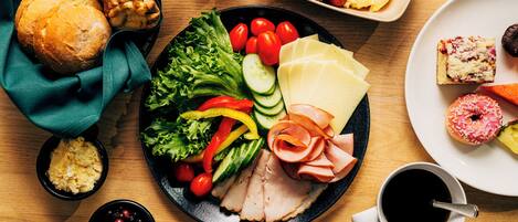 A variety of food items on a table, including bread, vegetables, cheese, and meat.