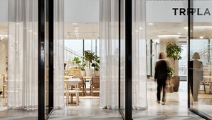 A modern interior with glass doors, a visible store named "TRPLA" on the right, and a person walking inside. - Original Sokos Hotel Tripla (Helsinki)