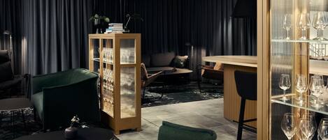 Un área de estar moderna con un sofá, sillones, una mesa de centro y una zona de bar con copas de vino.