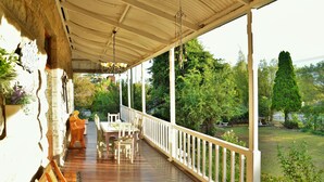 A covered porch with wooden flooring, white railings, and a table with chairs. - Die Kliphuis Standerton (Lekwa)