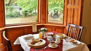 A breakfast table set with plates of food, a menu, and a vase of flowers. - Die Kliphuis Standerton (Lekwa)