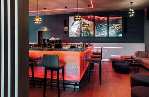 Un espace bar moderne doté d’un comptoir, de sièges et offrant une vue sur le paysage urbain.