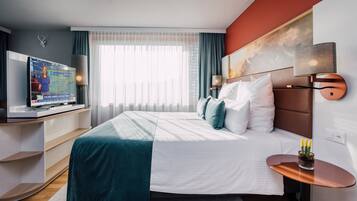Ein modernes Hotelzimmer mit einem großen Bett, einem Fernseher und Blick ins Freie.