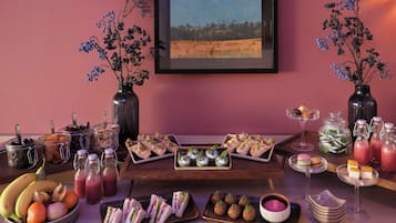 A table set with various food items, including sandwiches, pastries, and fruit.