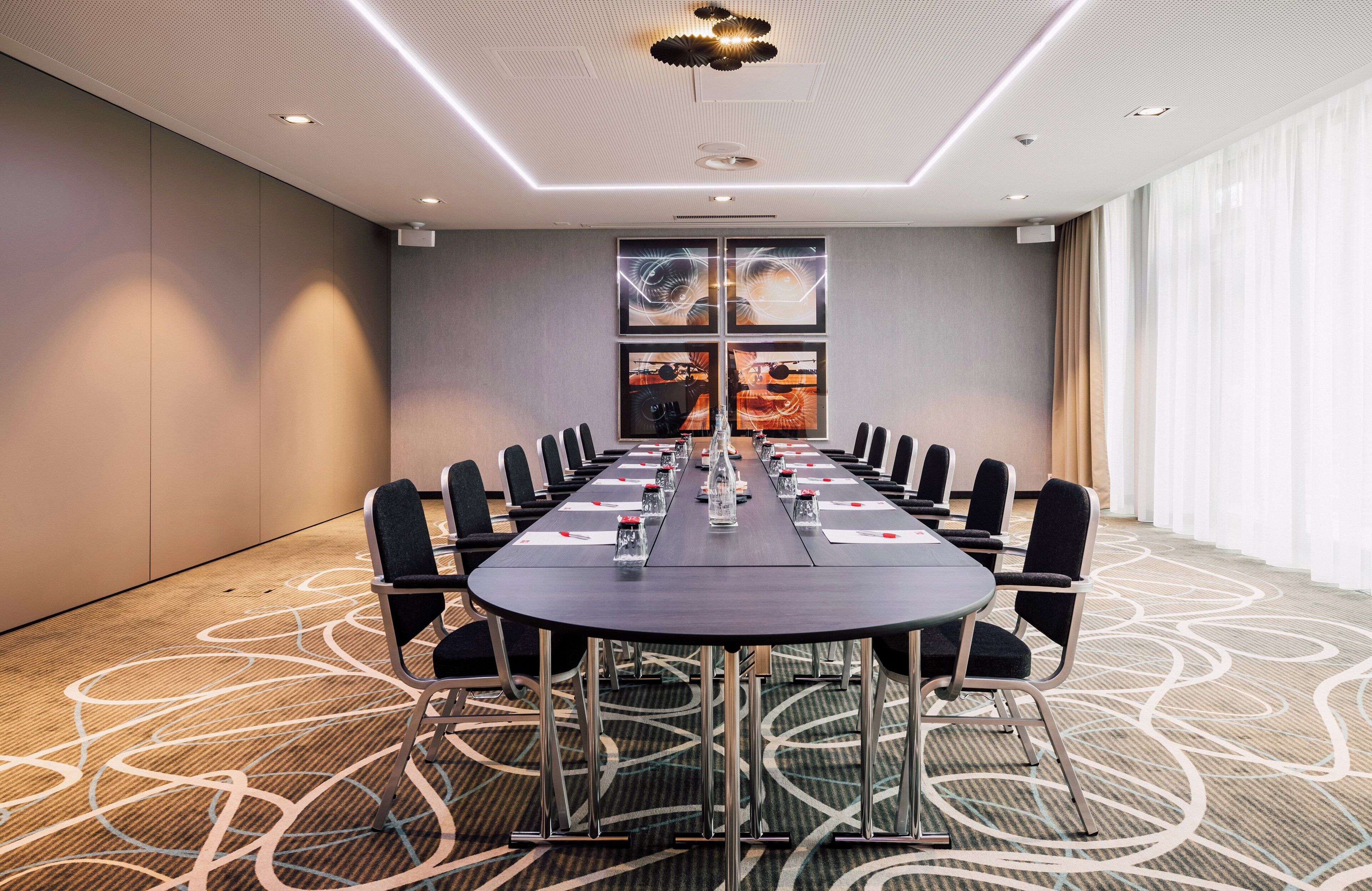 A conference room with a long table, chairs, and a patterned carpet.