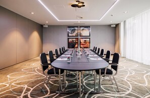 Un salón de conferencias con una mesa larga, sillas y una alfombra estampada.