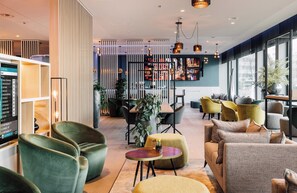 Ett modernt loungeområde med sittplatser, en bar och utsikt över staden.