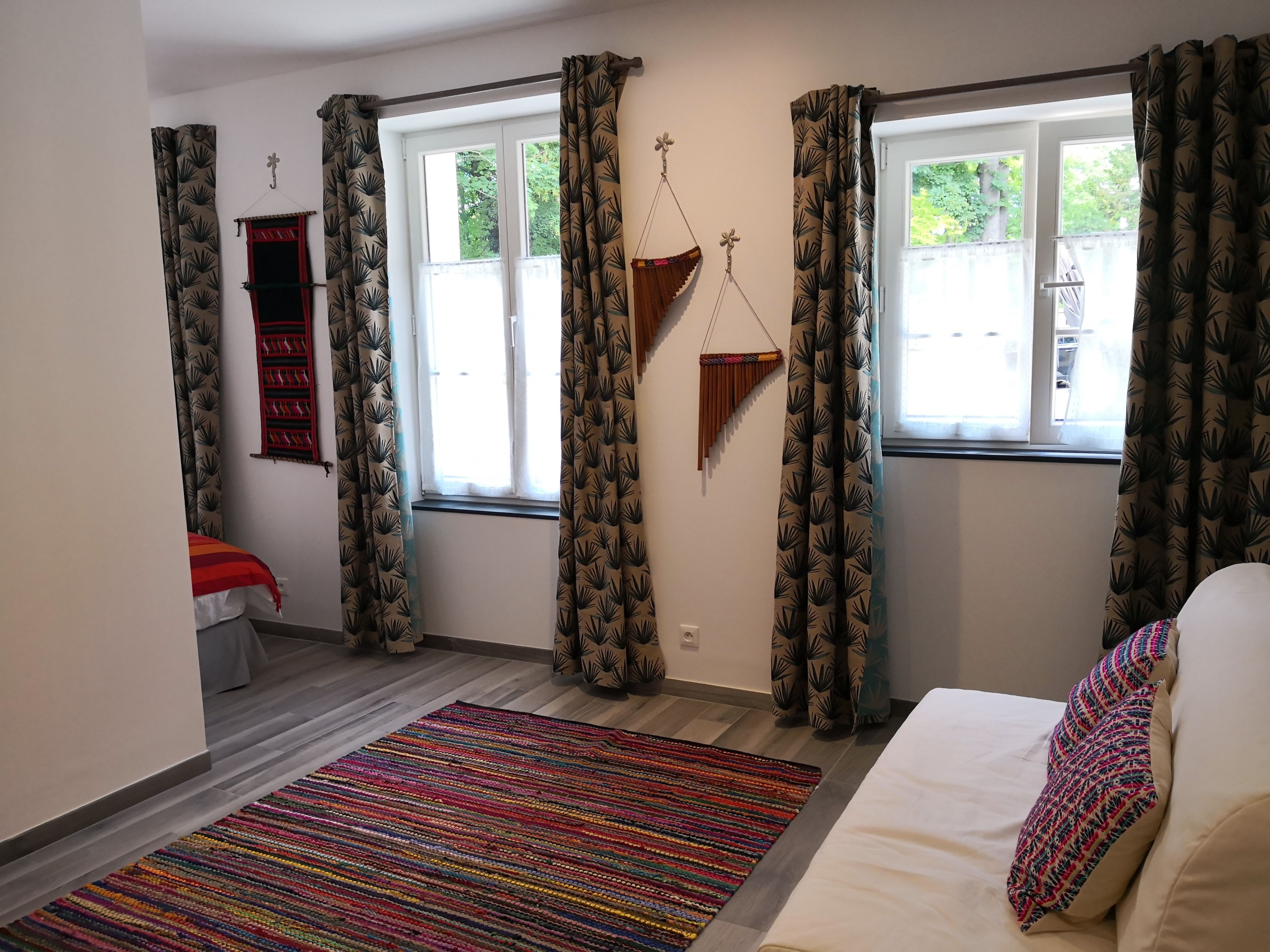 A room with a bed, a colorful rug, and patterned curtains.