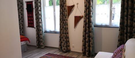 A room with a bed, a colorful rug, and patterned curtains.