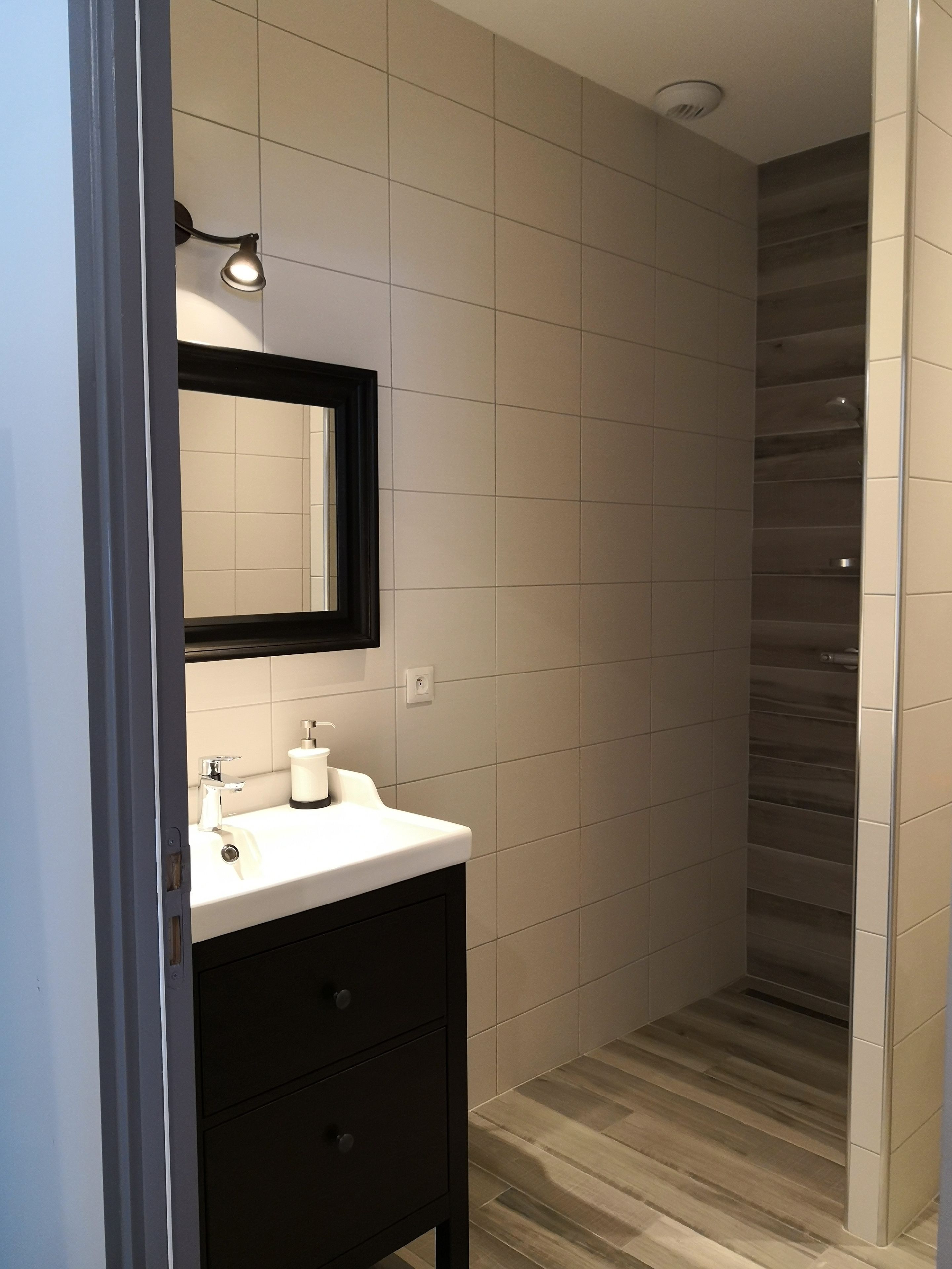 A modern bathroom with a white sink, dark vanity, and a mirror.