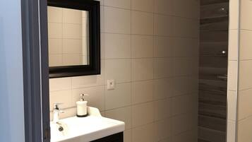 A modern bathroom with a white sink, dark vanity, and a mirror.