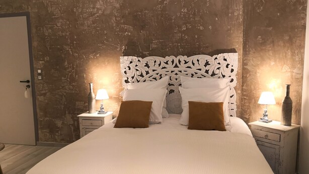 Une chambre avec un grand lit, deux tables de chevet avec des lampes et un mur à motifs derrière le lit.