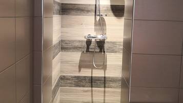 Une salle de bain avec une douche, des murs carrelés et des toilettes.